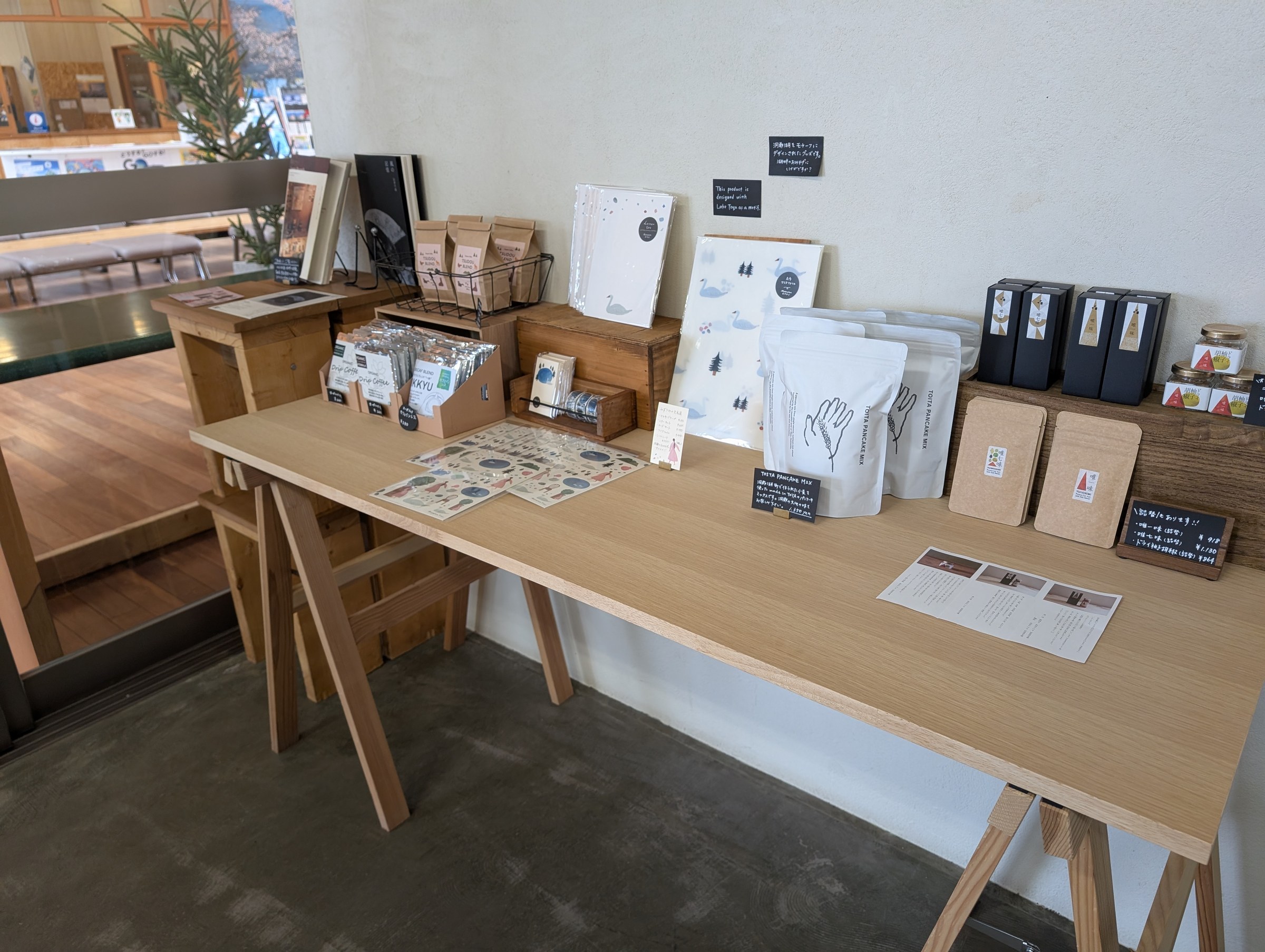 TSUDOUの物販コーナー。ドリップコーヒー、洞爺湖モチーフのポストカードやステッカー、パンケーキミックスなどが並ぶ