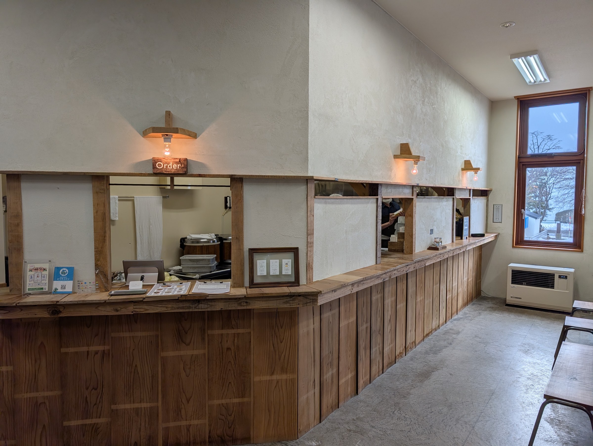 TSUDOUの注文カウンター。木の板を貼り合わせたカウンターに「Order」の看板、奥に厨房が見える
