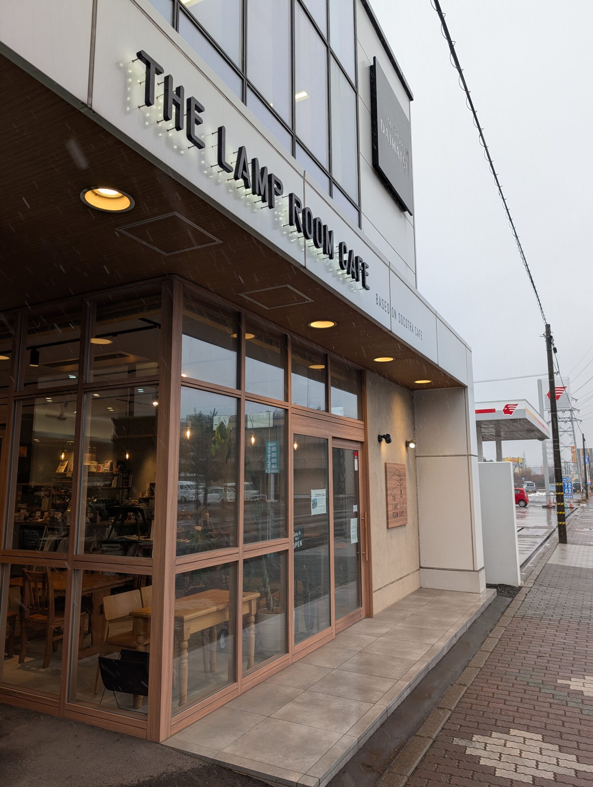 THE LAMP ROOM CAFEの外観。グレーの建物に電球風のサインレター