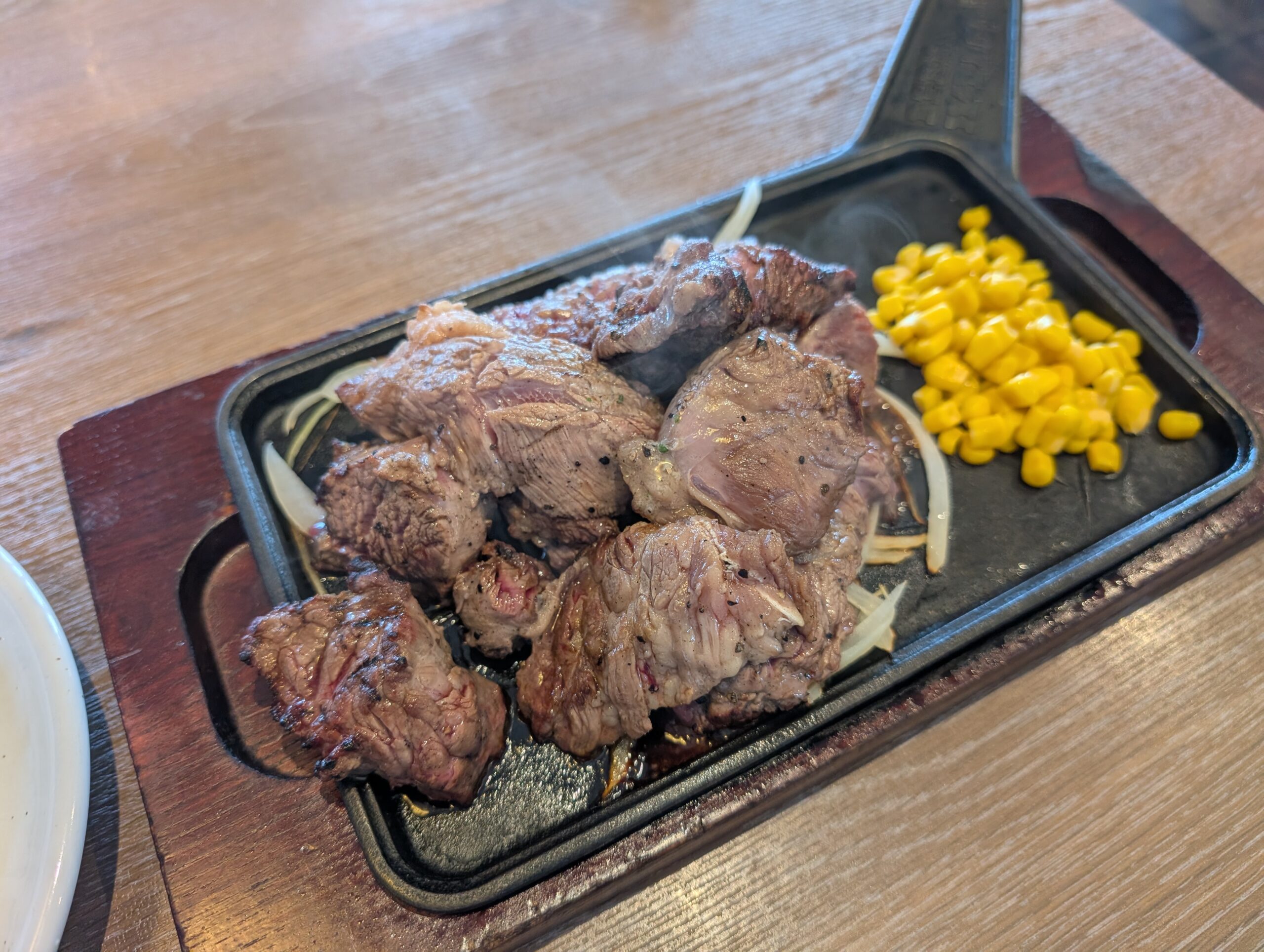 鉄板の上の炭焼きカットステーキとコーン