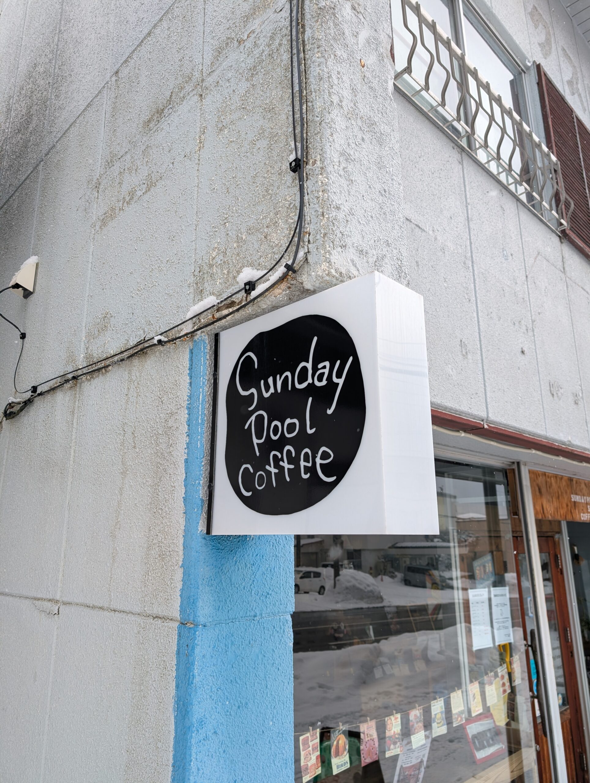 Sunday Pool Coffeeの看板。黒丸に白い手書き文字のロゴ