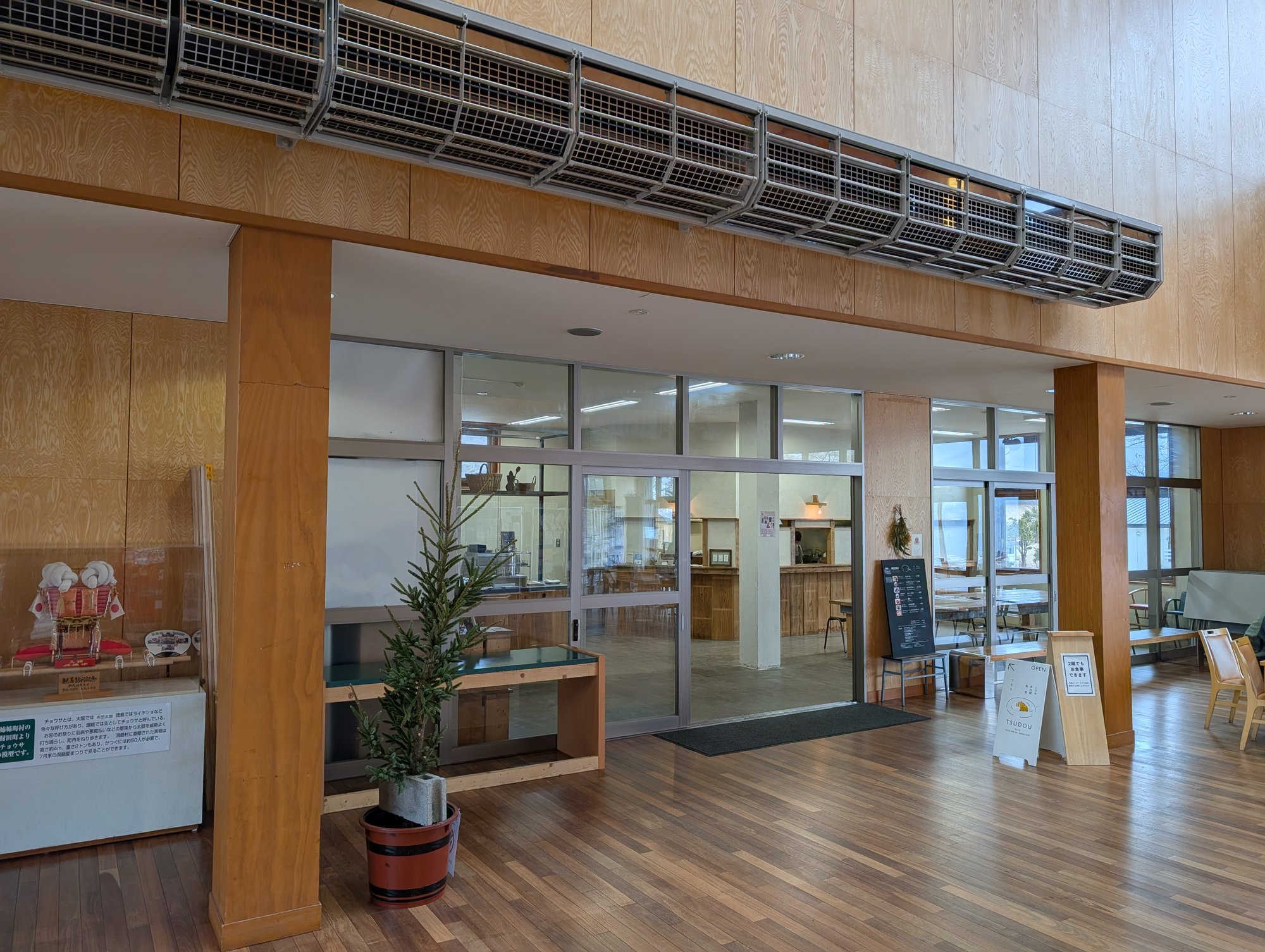 館内からTSUDOUの入口を望む。ガラスの仕切りの奥にカウンターと看板メニューが見える