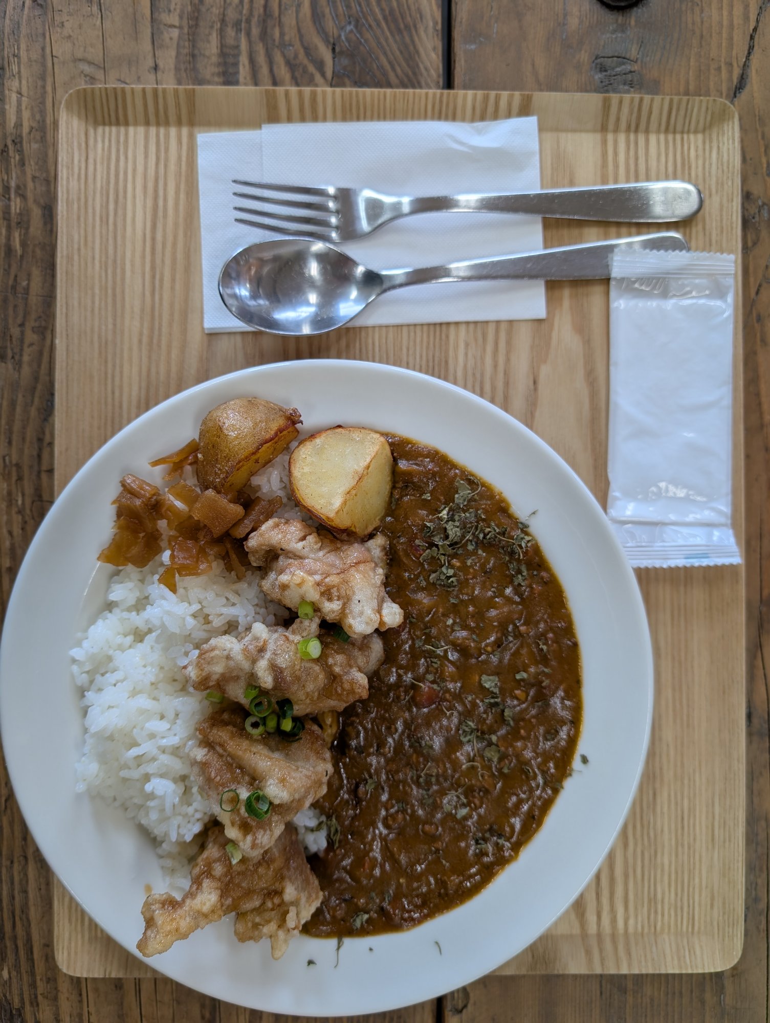 からあげカレー。白いライスの上にゴロっとした唐揚げと洞爺じゃがいも、福神漬け。濃い色のカレールーがたっぷり